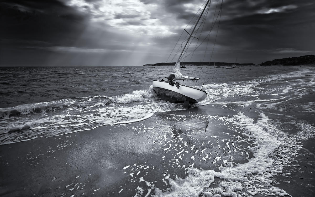 Black and white photograph of Sailboat Stranded On The Beach After A Storm